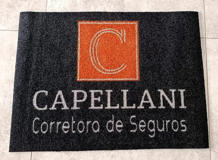 Tapete de nylon preto com a logo da Capellani Corretora de Seguros em laranja e branco