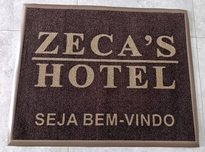 Tapete de nylon marrom com o nome Zeca’s Hotel e a frase de boas vindas