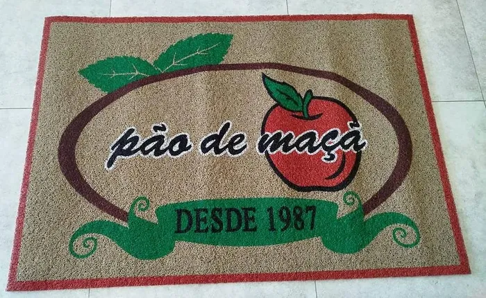 Capacho de vinil bege com a logo colorida da padaria Pão de Maçã