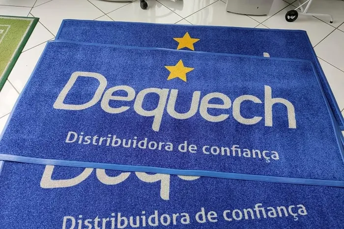 Tapetes de nylon azuis com a logo da Dequech Distribuidora em branco e as estrelas amarelas
