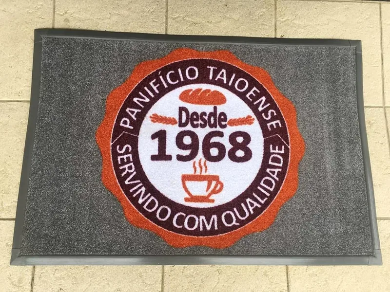 Tapete de nylon com o selo colorido do Panifício Taioense, desde 1968