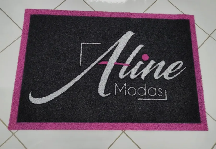 Capacho de vinil emborrachado preto com borda pintada de rosa e a logo da Aline Modas